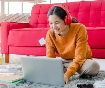 Image of teenage girl working on her laptop surrounded by paper, notepads, and stick notes.